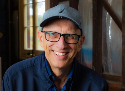 Greg Woodland author portrait wearing baseball cap and glasses